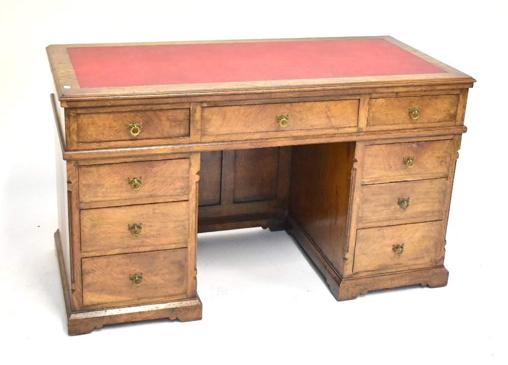 A 19th century pollard oak kneehole desk with an arrangement of nine drawers raised on plinth