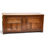 A large reproduction oak sideboard with carved frieze above twin panelled doors enclosing single