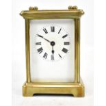 A brass cased carriage clock, the circular dial set with Roman numerals, height excluding swing