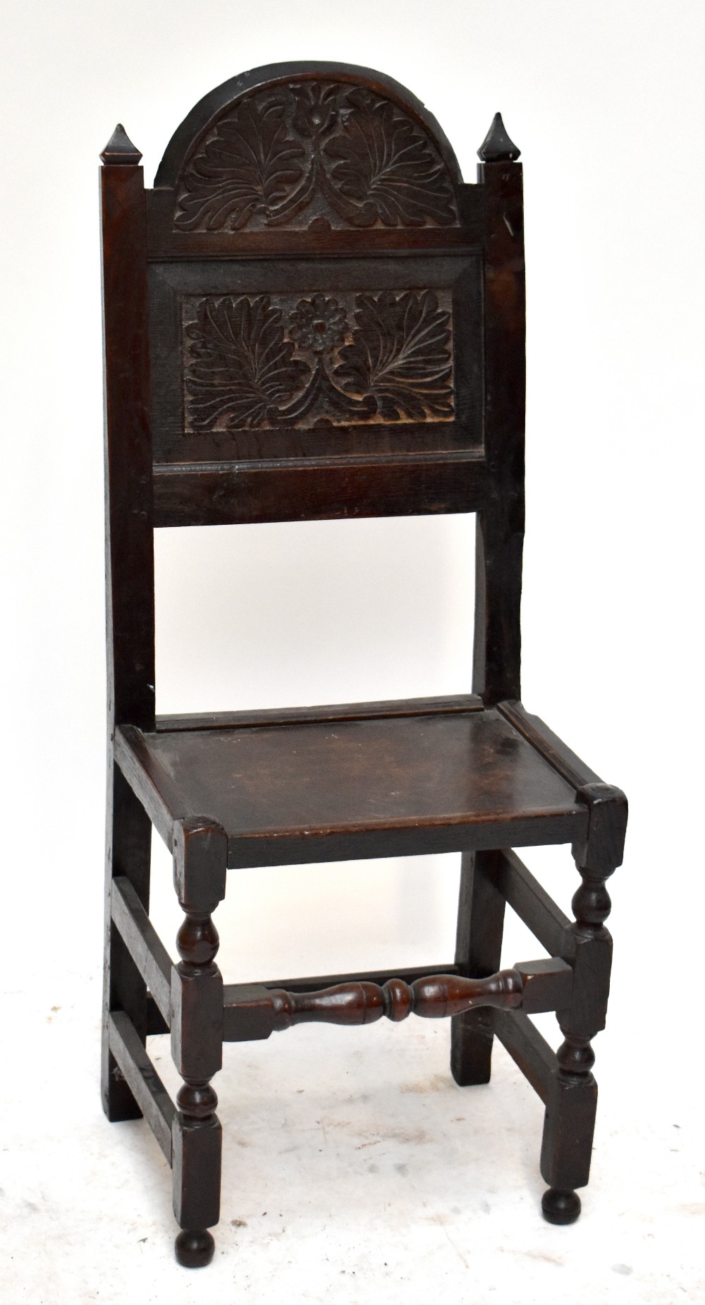 A 19th century oak Wainscot type single chair with carved decoration to back panel, raised on bun