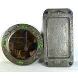 An Arts & Crafts sheet pewter circular wall mirror, with repoussé floral decoration and four green