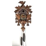 A circa 1900 Black Forest carved stained beech cuckoo clock featuring leaf and bird decoration