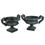 A pair of French 19th century cast iron twin handled urns raised on square section bases, width
