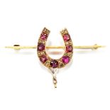 A yellow metal horse shoe brooch set with seven garnet's and sixteen white stone chips, apparently