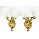 A pair of gilt metal twin sconce wall lights of curved tapered form with cherub and wreath fixtures,