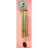 A set of brass chimes with shield shaped wall mount.