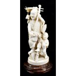 An early 20th century carved ivory okimono depicting gentleman with instrument and child with saki