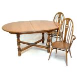 ERCOL; an elm dining suite comprising extending oval table with one extra leaf, raised on bun