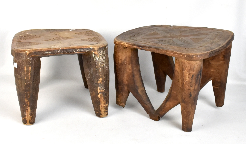 Two African tribal art stools, each with carved decoration, raised on fluted column supports,