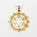 A yellow metal Star of David motif pendant within scroll border, stamped 750 to bail, diameter
