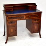 An Edwardian Sheraton Revival kneehole desk, with four drawers above two panelled cupboard doors,