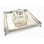 BARKER BROTHERS; a George V hallmarked silver mounted glass inkwell on square section stand to