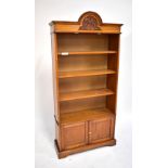 An early 20th century oak free standing bookcase, with three fixed shelves above two base cupboard