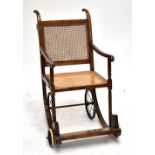 An early 20th century oak invalid's 'Eastbourne Chair' with rattan seat and back.