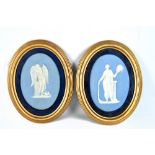 WEDGWOOD; a pair of pale blue oval relief moulded plaques, one depicting an angel and the other of a