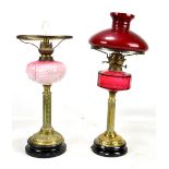 Two oil lamps with cranberry and pink glass reservoirs respectively, one with opaque red and white