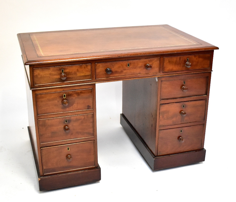 A mahogany twin pedestal desk with inset gilt tooled leather top above arrangement of nine