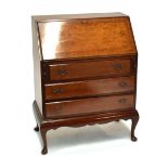 A reproduction burr walnut veneered bureau, with three drawers and raised on cabriole supports,