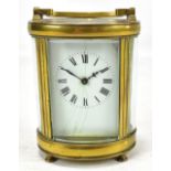 A late 19th/early 20th century French brass cased carriage clock of oval form, the white enamelled