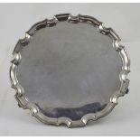 A George VI hallmarked silver salver with cast scalloped edge, raised on three scrolling feet,