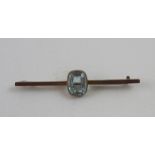 An Edwardian 9ct gold bar brooch with central emerald-cut aquamarine-coloured stone, approx 4g.