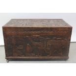 An early 20th century oak bedding box, profusely carved with South Pacific themed panels to top,