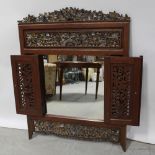 A hardwood and gilded wall mirror in the Eastern style with carved fretwork and border above twin