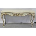 An ornate French-style cream console table, carved decoration to the front, to cabriole supports,