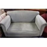 An Edwardian two-seat sofa, scrolling arms to castors,