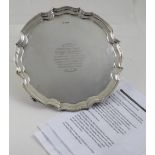 A George V hallmarked silver salver with curving rim to four scrolling supports,