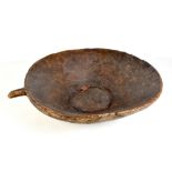 A large primitive carved bowl with handle and patchwork repair, length 65cm.
