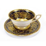 ROYAL WORCESTER; a floral painted and gilt heightened cabinet cup and saucer signed by Ernest