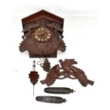 A late 19th century Black Forest carved oak wall hanging cuckoo clock with bird surmount, complete