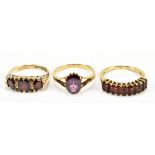 A 9ct yellow gold garnet set dress ring, size J, and two further similar 9ct yellow gold rings,