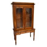 A French 19th century walnut bookcase with twin glazed doors enclosing three shelves on associated
