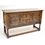 An early 20th century carved oak sideboard with two central narrow drawers flanked by two carved