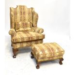 A wing back armchair with floral spray upholstery on oak cabriole front legs and a foot stool on