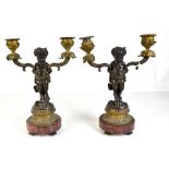 AFTER CLODION; a pair of bronze figural two branch candlesticks with grape and vine sconces on