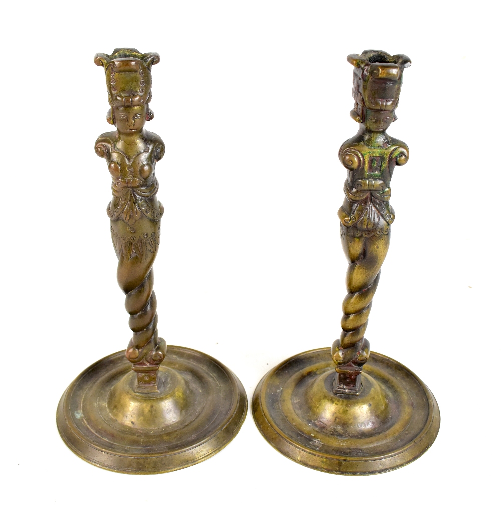 A pair of Aztec style bronze candlesticks raised on circular dish bases, height 31cm.