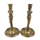 A pair of Aztec style bronze candlesticks raised on circular dish bases, height 31cm.