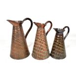 A graduated set of three Arts and Crafts copper jugs in the manner of J.S & S with lidded skin