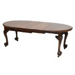 An early 20th century mahogany wind-out extending dining table with two extra leaves, raised on