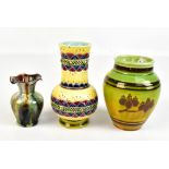 An art pottery vase with raised moulded decoration on a yellow/green ground, impressed marks to base