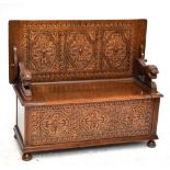 A reproduction carved oak monk's bench, with carved and panelled front section and rotating top,