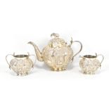 An Indian white metal three piece tea service, each piece with serpent handles and repoussé