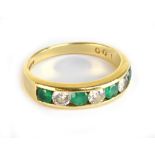 An 18ct yellow gold diamond and emerald channel set seven stone ring, the four emeralds weighing