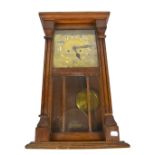 An early 20th century oak cased wall clock, the brass dial set with Arabic numerals, height 59cm.