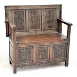 A reproduction carved and panelled oak monk's bench, width 99cm.
