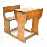 A mid-20th century oak children's desk with integrated seat.