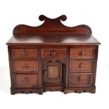 A Victorian miniature mahogany dresser base with shaped raised back, moulded rectangular top, an